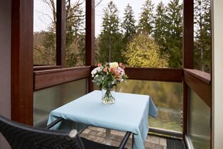 Balkonsitzplatz mit Tisch, Stuhl und Waldblick